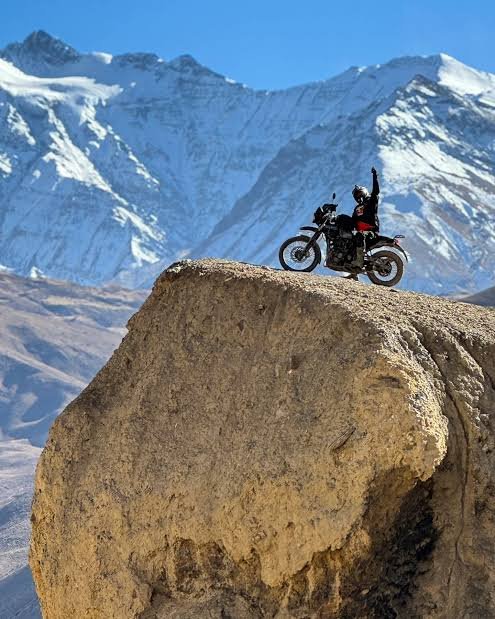 Rider on a rock edge with snow peaks behind, Upper Mustang
