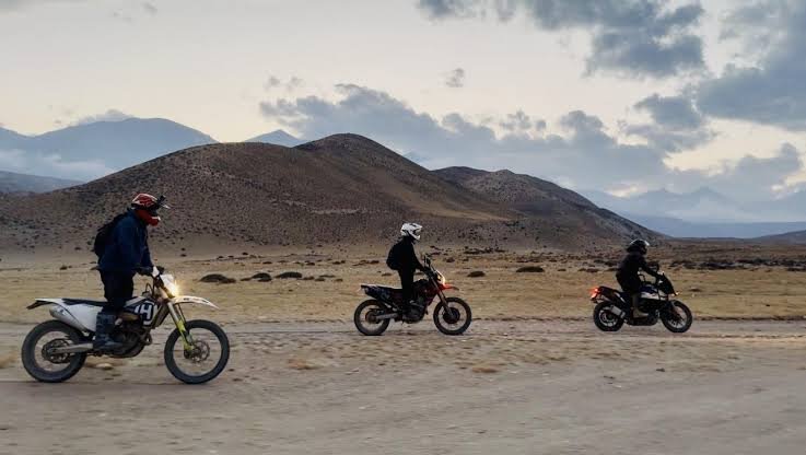 Three riders cross a high-altitude plateau at dusk